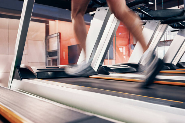 フィットネス、運動のためにマシン上で実行している男とのトレッドミル、心血管や心臓の健康のための心臓トレーニングやワークアウト。速いスピードで走るためのエネルギー、スピード、コミットメントを持つアスリートの足. - 写真・画像