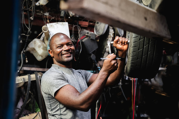 Retrato de reparos mecânicos e inspeciona a suspensão do carro em detalhes na garagem. - Foto, Imagem