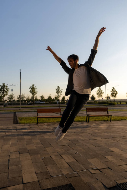 young attractive dancer in casual cloth doing ballet jump on the urban background. Contemporary dance, modern choreography. High quality photo - Фото, зображення