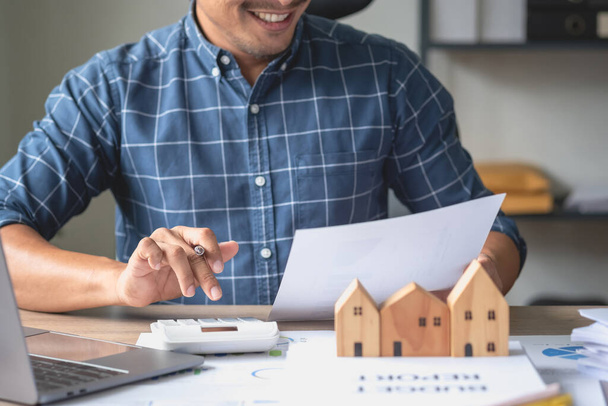 Accountant, businessman, real estate agent, businessman handing model house to customers along with house interest calculation documents for customers to sign. - Photo, image
