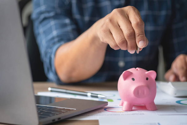 Mann hält eine Münze, um ein Sparschwein fallen zu lassen Um Geld für die Zukunft der Familie zu sparen, Ideen zu retten. - Foto, Bild