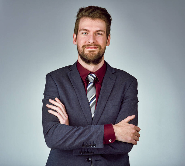 Style inspired by success. Studio portrait of a handsome young businessman posing confidently against a gray background - Photo, image