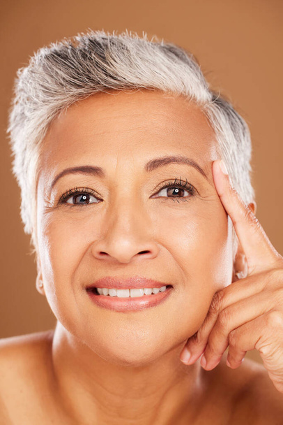 Face, beauty and skincare with a senior woman in studio on a brown background for wellness or natural care. Facial, portrait and cosmetics with a mature female to promote a product for perfect skin. - Foto, Imagen