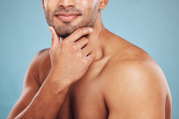 Hand, skincare and beauty with a man model in studio on a blue background thinking about grooming. Wellness, cosmetics and skin with a male posing to promote a natural product or antiaging treatment. - Foto, Bild