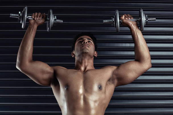 Lift it. a handsome young man working out with dumbbells - 写真・画像