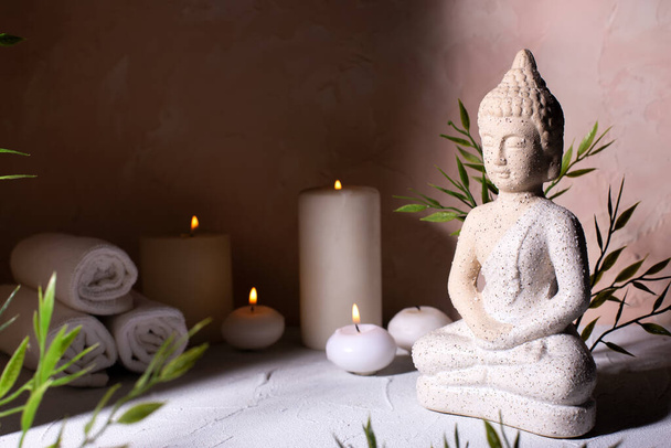 Beauty wellness concept with statue of Buddha with burning candles for spa time.  Religion concept.  - Foto, immagini