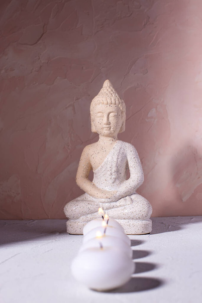 Wellness concept with  row of burning candles and statue of Buddha  on textured background.  Religion concept. Selecctive focus is on Buddha. - 写真・画像