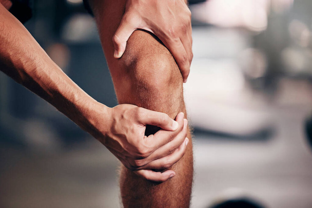 Fitness, exercise and man with knee pain in the gym, closeup of hands holding knee after injury. Sports, health and hurt male athlete with sore joint in leg after workout, training and exercising. - Foto, immagini