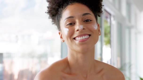 Facial, black woman and skincare in a bathroom for beauty, face cream and skin wellness, pamper and relax while grooming. Portrait, woman and face product after a shower, hygiene and daily routine. - Footage, Video