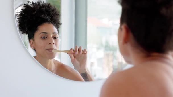 Mirror, black woman and brushing teeth in bathroom, wellness or hygiene to clean, dental care or routine. Oral health, African American female or tooth brush with toothpaste for fresh breath or smile. - Footage, Video