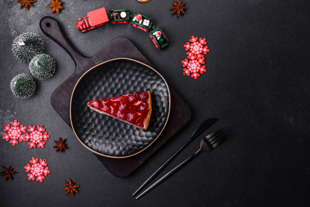 Домашний вкусный чизкейк с желе и малиной ягодами на черной тарелке на темно-бетонном фоне - Фото, изображение