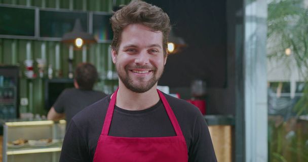 Portret szczęśliwej młodej baristki uśmiechniętej do kamery z bliska. mężczyzna pracownik mały biznes kawiarnia plac - Zdjęcie, obraz