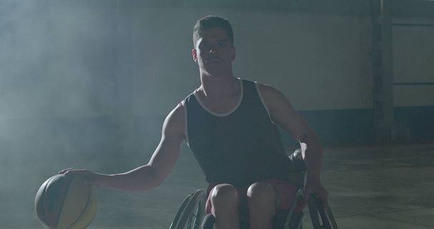 Portret van een Braziliaanse verlamde atleet in een rolstoel die basketbal speelt op het sportveld, kijkend naar de camera - Foto, afbeelding