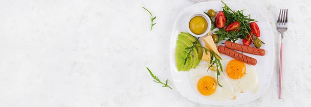 Café da manhã inglês - ovos fritos, linguiças, tomates, abacate, queijo e azeitonas. Comida americana. Vista superior, banner - Foto, Imagem