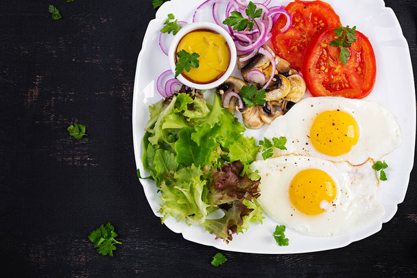 Ketogenní jídlo. Smažená vejce, houby a rajčata. Keto, paleo snídaně. Pohled shora, režie, kopírovací prostor - Fotografie, Obrázek