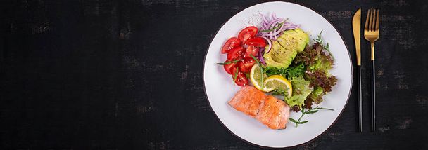 Ketogenic diet breakfast. Baked salmon salad with greens, tomatoes, red onions and avocado. Keto, paleo lunch. Top view, banner - 写真・画像