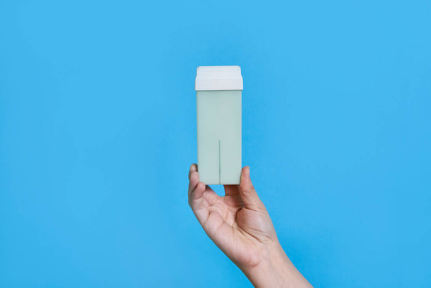 someones hand holding an empty white box on a blue background with copy space in the concept of online marketing - Foto, imagen