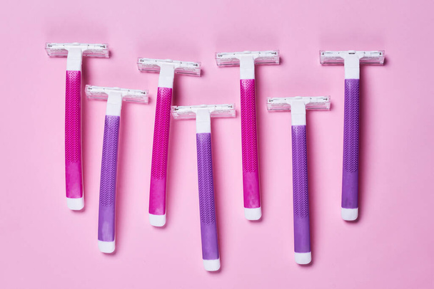 three purple and white razors on a pink background with copy space in the top right handout is shown - 写真・画像