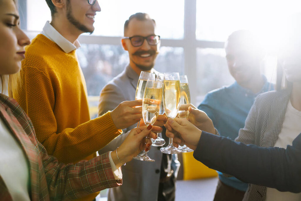 Toasting to success concept.Group of young business people toasting each other and smiling while standing in the office. Celebration and festive concept. - Photo, image