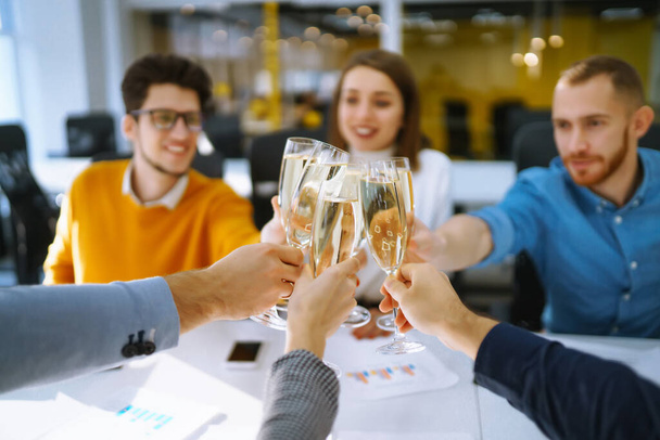 Toasting to success concept.Group of young business people toasting each other and smiling while standing in the office. Celebration and festive concept. - Foto, Imagen