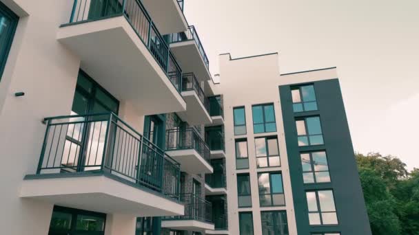 Buiten een modern hoogbouw gebouw. Modern woongebouw met meerdere verdiepingen en ramen en grote balkons. - Video