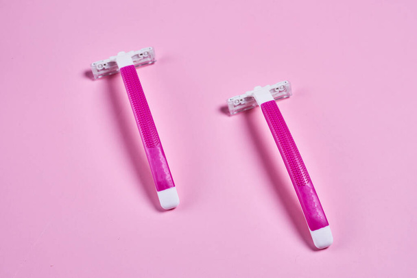 dos cepillos de dientes sobre un fondo rosa, uno es blanco y el otro es de color rosa brillante con una raya naranja - Foto, imagen