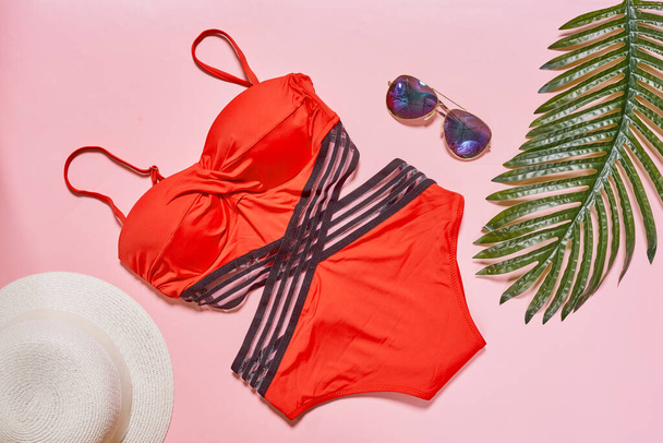 a bikini top, hat and sunglasses on a pink background with palm leaves in the fore - eyeglasses - Fotó, kép
