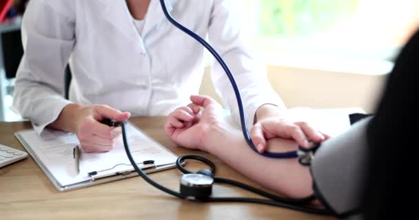 Médico cardiólogo midiendo la presión arterial al paciente en clínica. Hipertensión esencial e hipertensión arterial - Imágenes, Vídeo