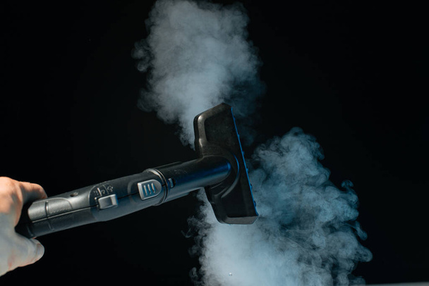 Steam clean brush in hand on black background. Clean concept. - Фото, изображение