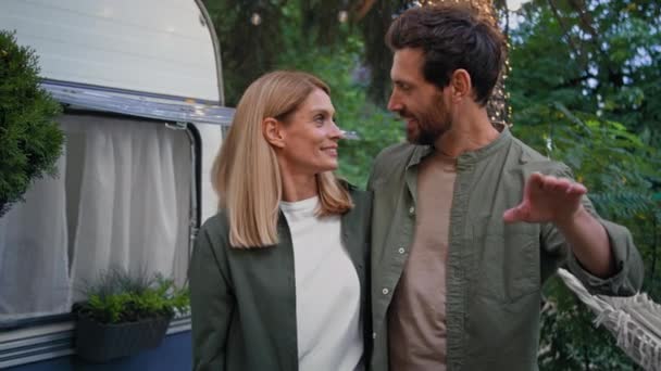 Spouses Caucasian woman and man married couple husband and wife girlfriend and boyfriend walking outdoors in camping near van trailer house backyard talking planning dreaming future estate guy showing - Footage, Video