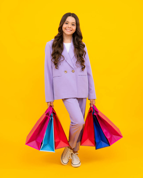 Verkaufs- und Einkaufskonzept. Teenager Mädchen mit Einkaufstaschen, isoliert auf Studiohintergrund - Foto, Bild