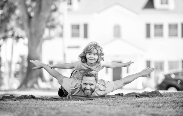 glad father with son relax together on green park grass, parenting. - 写真・画像