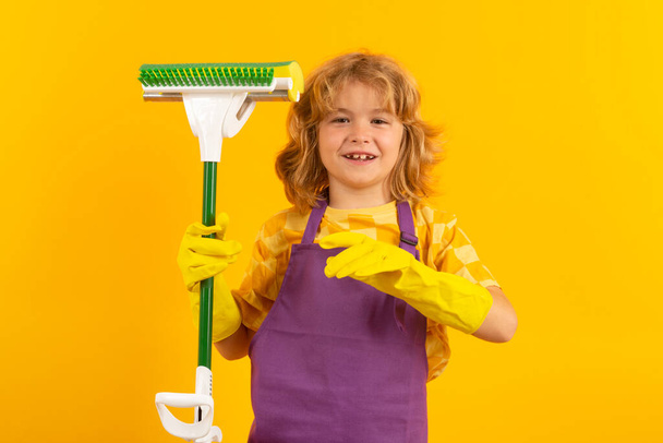 Child doing housework. Child cleans at home concept. Kid cleaning with mop to help with housework. Little cute boy sweeping and cleaning, isolated on studio color background - Photo, Image