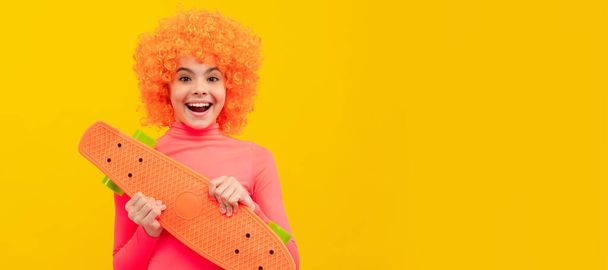 Chica cool feliz con el pelo naranja en rosa poloneck sonrisa sosteniendo pennyboard, monopatín. Divertido niño adolescente en la fiesta, encabezado del cartel del cartel con espacio de copia - Foto, imagen