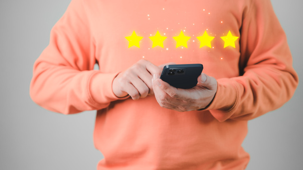 Man hand using a mobile phone with popup five star icon for feedback review satisfaction service and testimonial. Customer service experience and business satisfaction survey. - Photo, Image