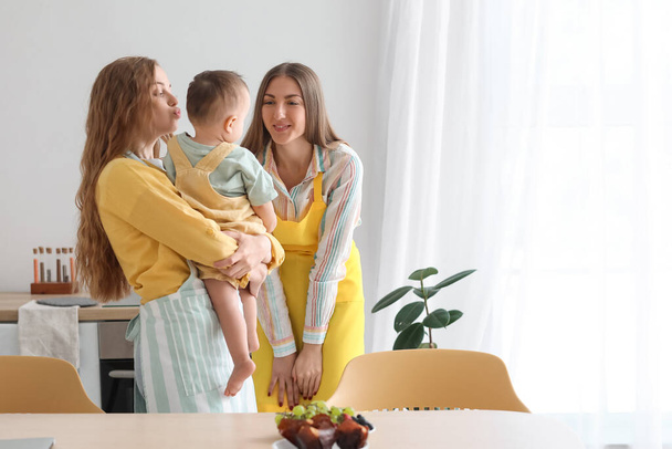 Szczęśliwa para lesbijek i ich małe dziecko z zabawką w kuchni - Zdjęcie, obraz