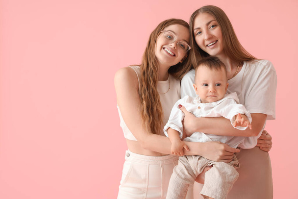 Happy lesbian couple with their little baby on pink background - Φωτογραφία, εικόνα