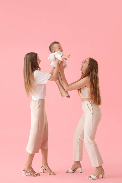 Happy lesbian couple with their little baby on pink background - Fotografie, Obrázek
