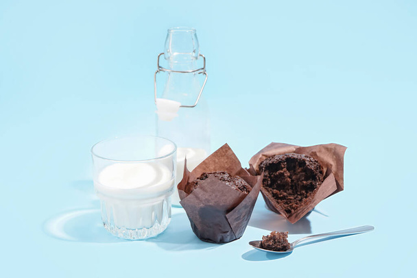 Sabrosas magdalenas de chocolate y vaso de leche sobre fondo de color - Foto, imagen
