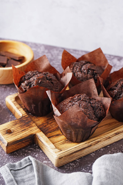 Wooden board with tasty chocolate muffins on grunge background, closeup - Foto, Imagem