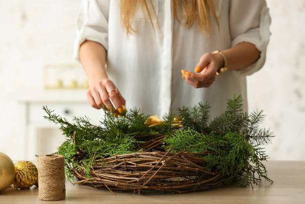 Woman making Christmas wreath at table, closeup - Foto, afbeelding