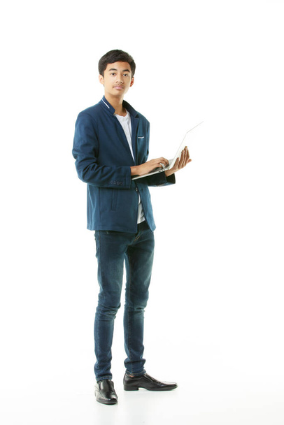 Fiatal középiskolás fiú, 15 éves, ázsiai fiatalember alkalmi ruhában, laptopot tart magánál tanuláshoz és kereséshez. Tini koncepció és oktatási technológia. - Fotó, kép