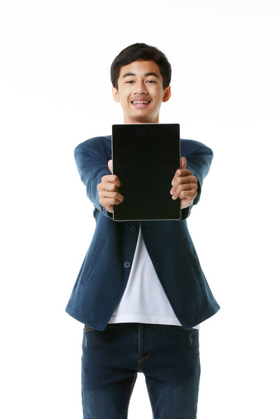 Ασιάτης μαθητής γυμνασίου 15 ετών που κρατά και δείχνει την κενή οθόνη του υπολογιστή tablet. Σύγχρονη έννοια εφηβική ζωή και την τεχνολογία. Στιγμιότυπο στούντιο απομονωμένο σε λευκό φόντο. - Φωτογραφία, εικόνα