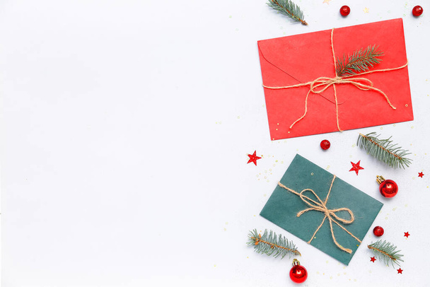 Σύνθεση με φακέλους, χριστουγεννιάτικα στολίδια και κλαδιά ελάτης σε ανοιχτό φόντο - Φωτογραφία, εικόνα