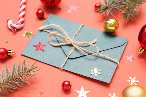 Composition with envelope, Christmas decorations and fir branches on red background, closeup - Foto, afbeelding