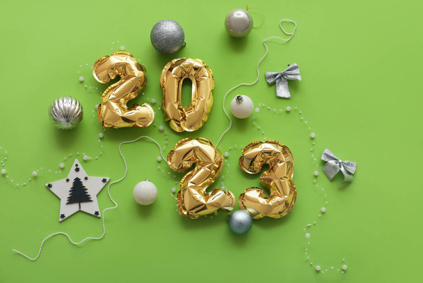 Figure 2023 made of balloons and Christmas decorations on green background - Valokuva, kuva