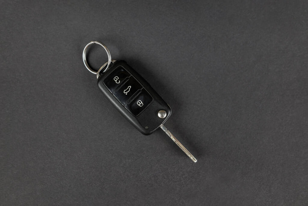 Nowoczesne kluczyki samochodowe odizolowane na czarnym tle z kopią miejsca na tekst. Składany klucz ze zdalnym alarmem i zwolnieniem bagażnika. Widok z góry. - Zdjęcie, obraz
