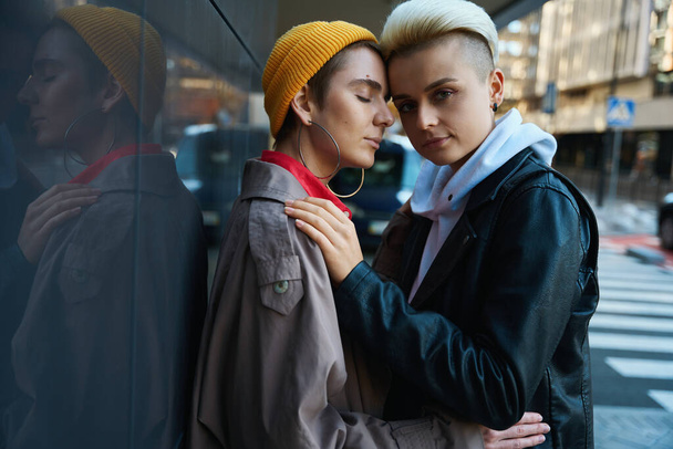 Two women hugging each other on a city street near modern buildings, they are an LGBT couple - Fotoğraf, Görsel