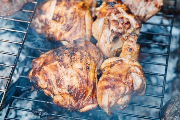 Chicken thighs Barbecue on The Hot Grill Close-up. Fire flames in the background - Fotó, kép