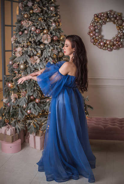 Winter holiday concept. Inspiration and fairy time. Woman near Christmas tree. Pretty nice lady in party dress, holidays days, magical night time - Photo, Image